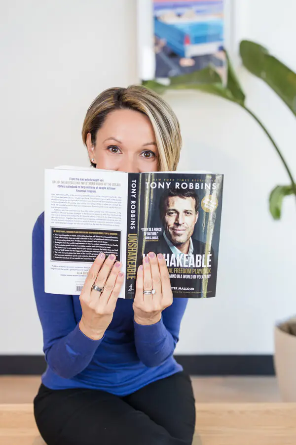 Diedra Perry holding a Tony Robbins book, reflecting her years working for the Anthony Robbins Company