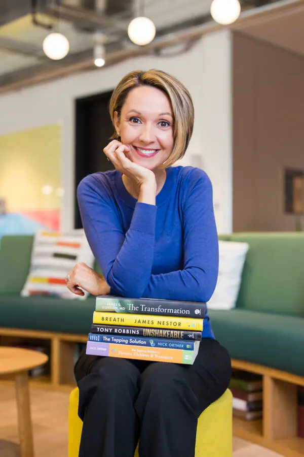 Diedra Perry, resilience coach, seated with a stack of personal growth books